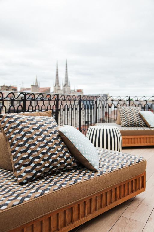 a row of beds with pillows on a balcony at Hôtel Singulier Bordeaux - Boutique Hôtel & Spa Anne Semonin in Bordeaux