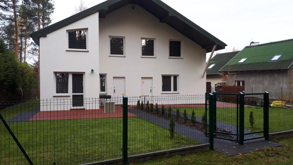 a white house with a fence in front of it at KOPALINO Apartamenty nad morzem in Kopalino