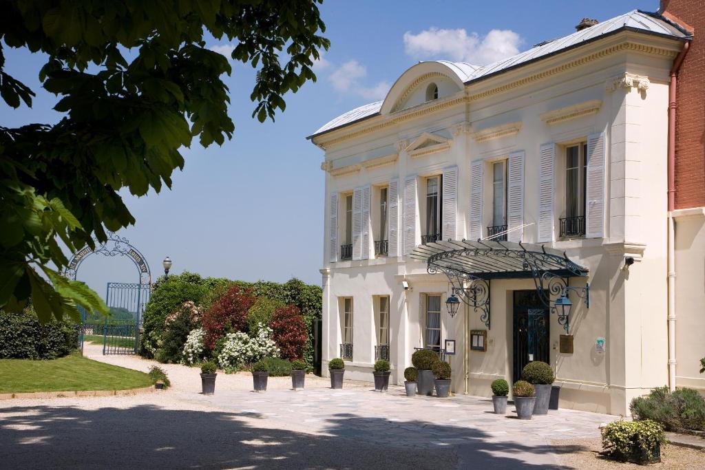 un edificio blanco con un patio delante en Pavillon Henri IV Hotel Restaurant Gastronomique Terrasse, en Saint-Germain-en-Laye