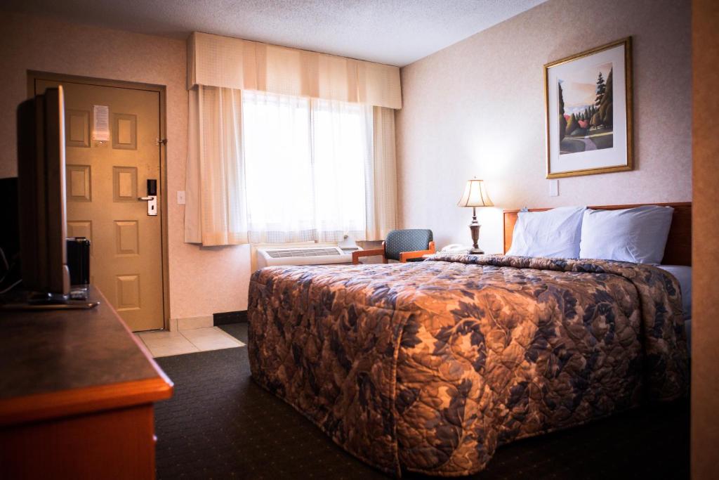 ein Hotelzimmer mit einem großen Bett und einem Fenster in der Unterkunft Langley Hwy Hotel in Langley