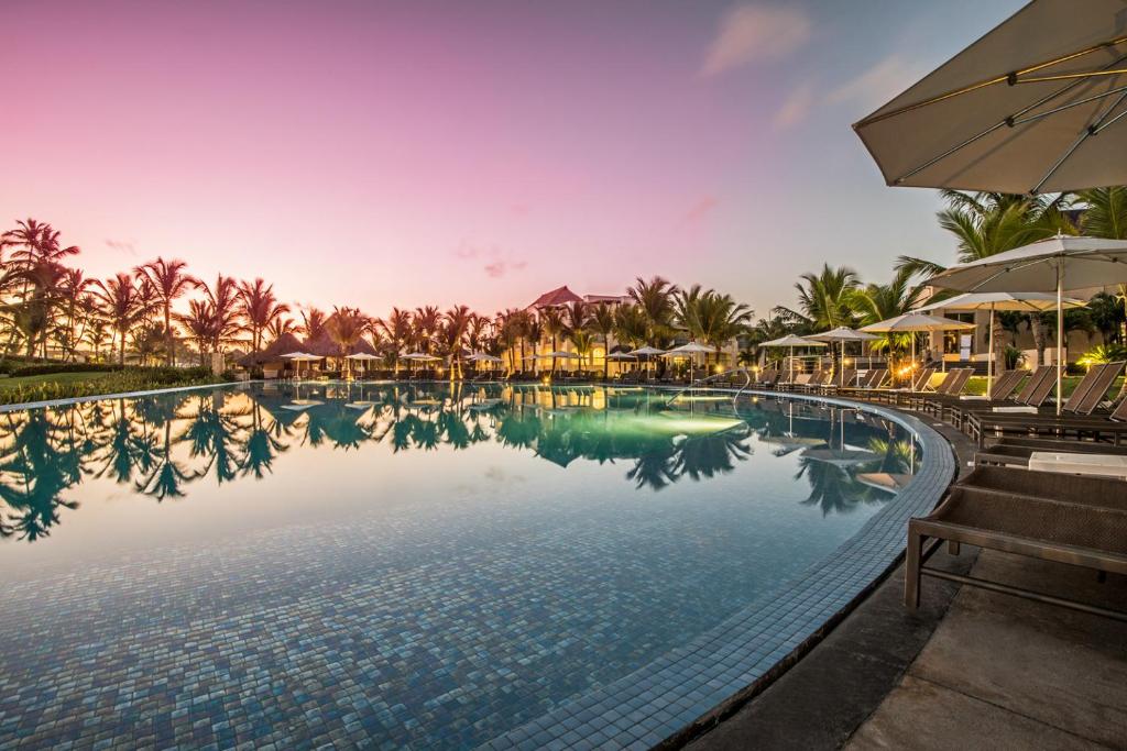 a swimming pool at a resort with an umbrella at Hard Rock Hotel & Casino Punta Cana - All Inclusive in Punta Cana