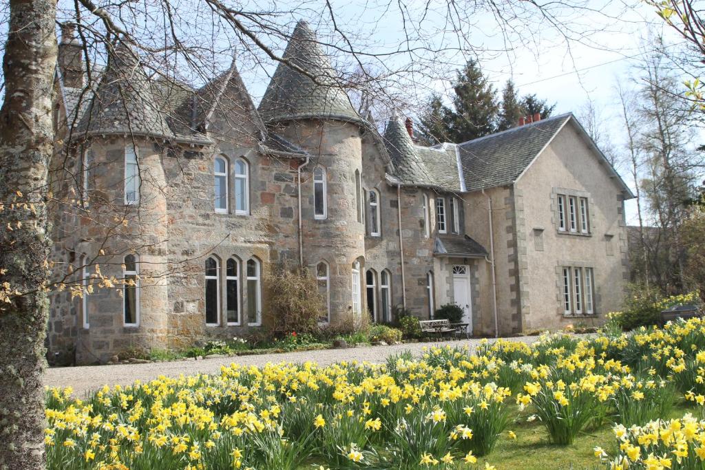 una vecchia casa in pietra con dei fiori davanti di Balvraid Lodge B&B a Inverness