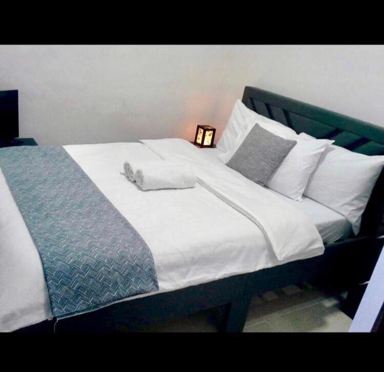 un grande letto con lenzuola e cuscini bianchi di Estien's cozy home a Malagasang Primero