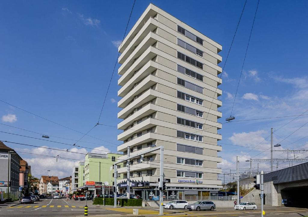 a tall white apartment building on a city street at Swiss Star Tower - Self Check-In in Zürich