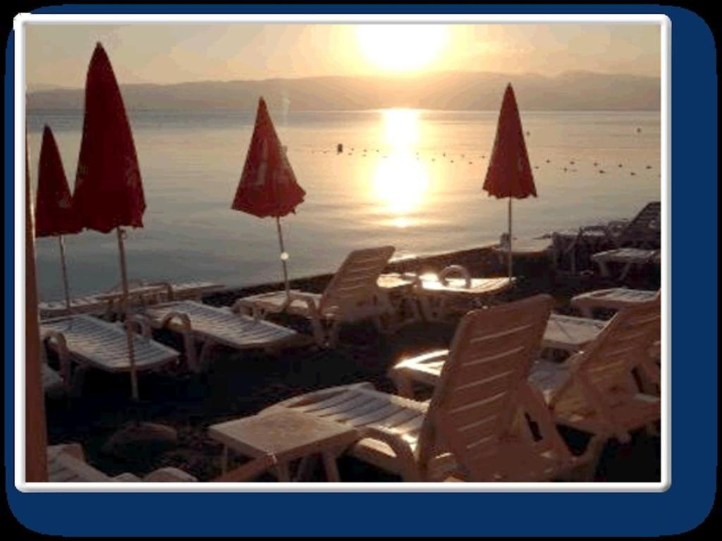 a group of chairs and umbrellas on a beach at Vila Ineks Ohrid in Ohrid