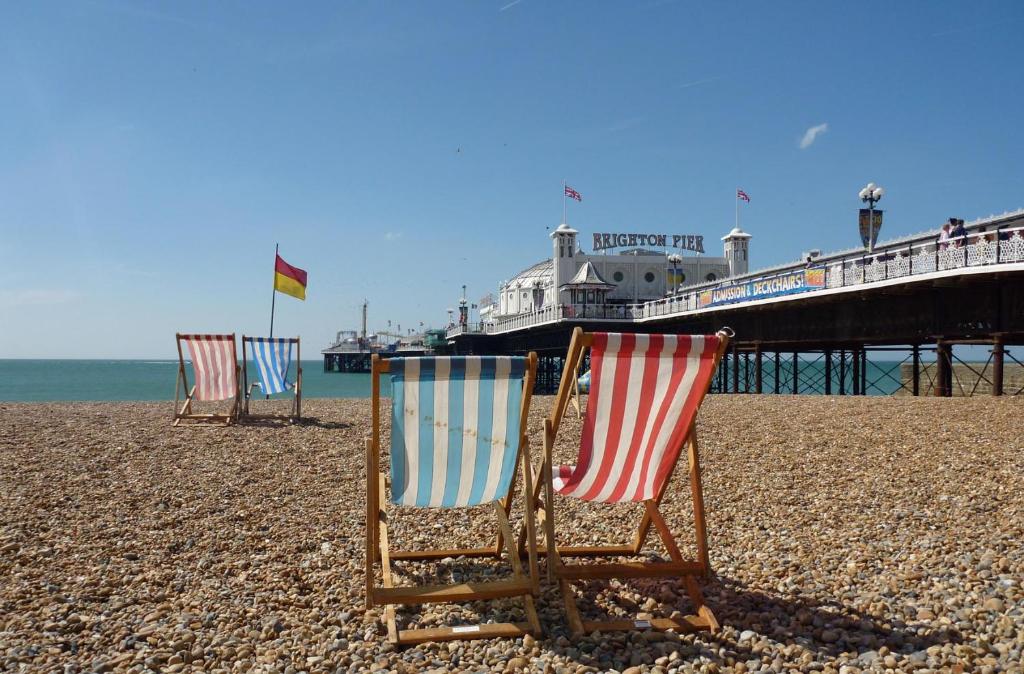 three chairs sitting on a beach near a pier at The Pearl - Stylish 3 Bedrooms house in great central location in Brighton & Hove