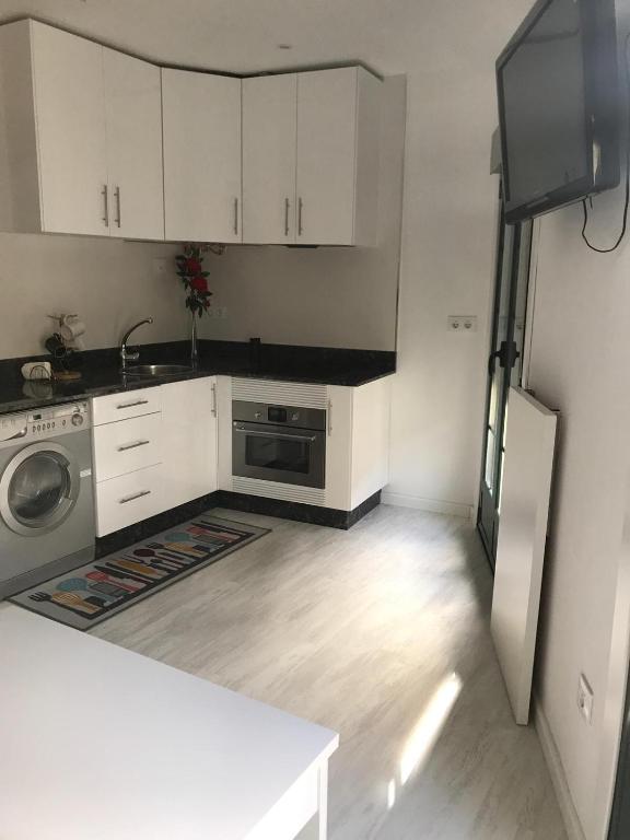 a kitchen with white cabinets and a sink and a refrigerator at Loft Casco Viejo 3 in Ourense