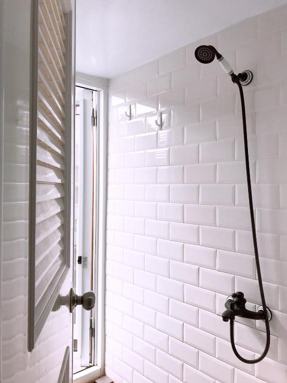 e bagno con doccia e parete piastrellata bianca. di Cong Sen Backpackers Hostel a Città di Taitung