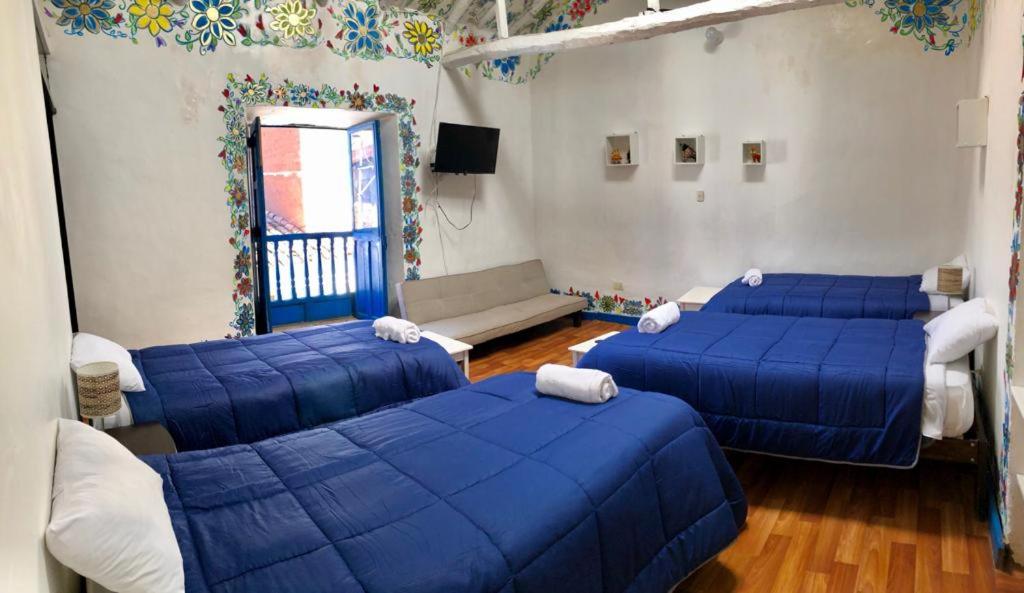 a room with three blue beds and a couch at Apartamento Cusco Queswa in Cusco
