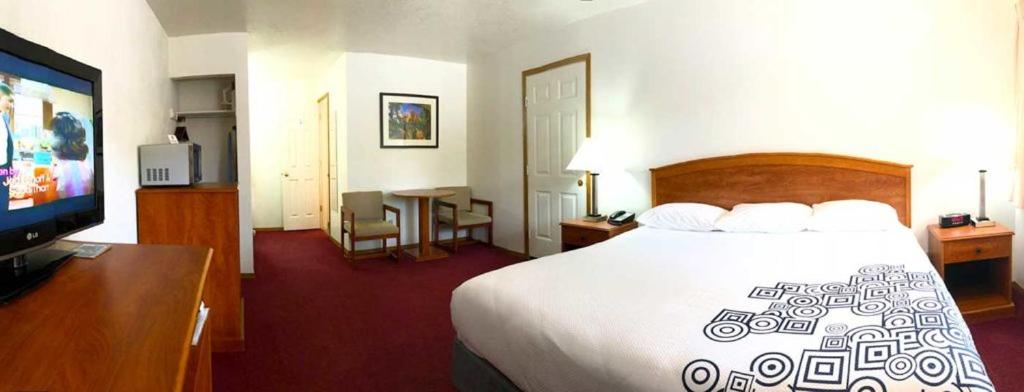 Habitación de hotel con cama y TV de pantalla plana. en Austin's Chuckwagon Motel, en Torrey
