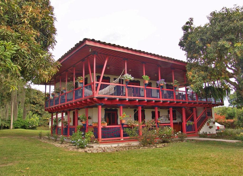 una casa roja con un balcón con flores. en Finca Cafetera El Balso, en Armenia
