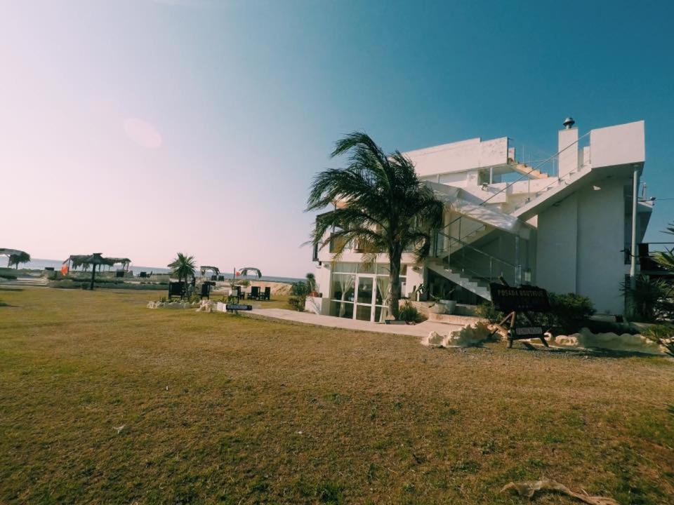 un bâtiment avec un palmier en face d'un champ dans l'établissement Punta Encanto Posada Boutique, à Miramar