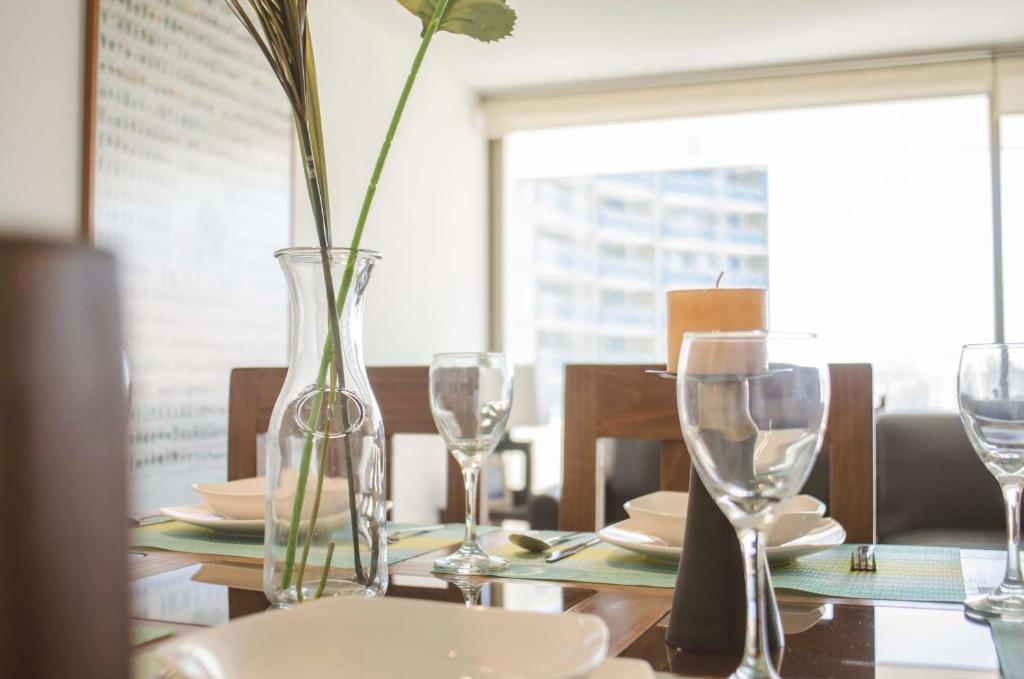 a table with glasses and a vase with a flower in it at Kennedy Premium Apartments II in Santiago