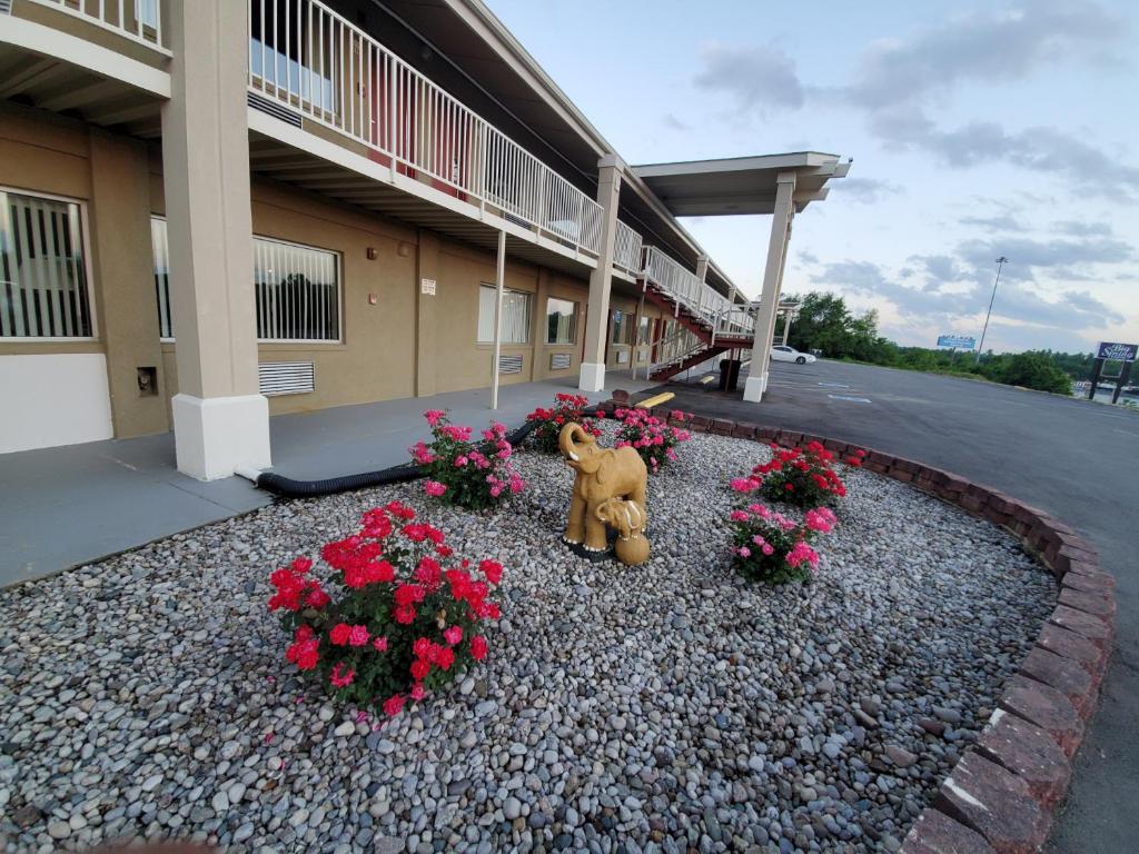 a teddy bear sitting in front of a building with flowers at Big Spring Inn Madisonville in Madisonville