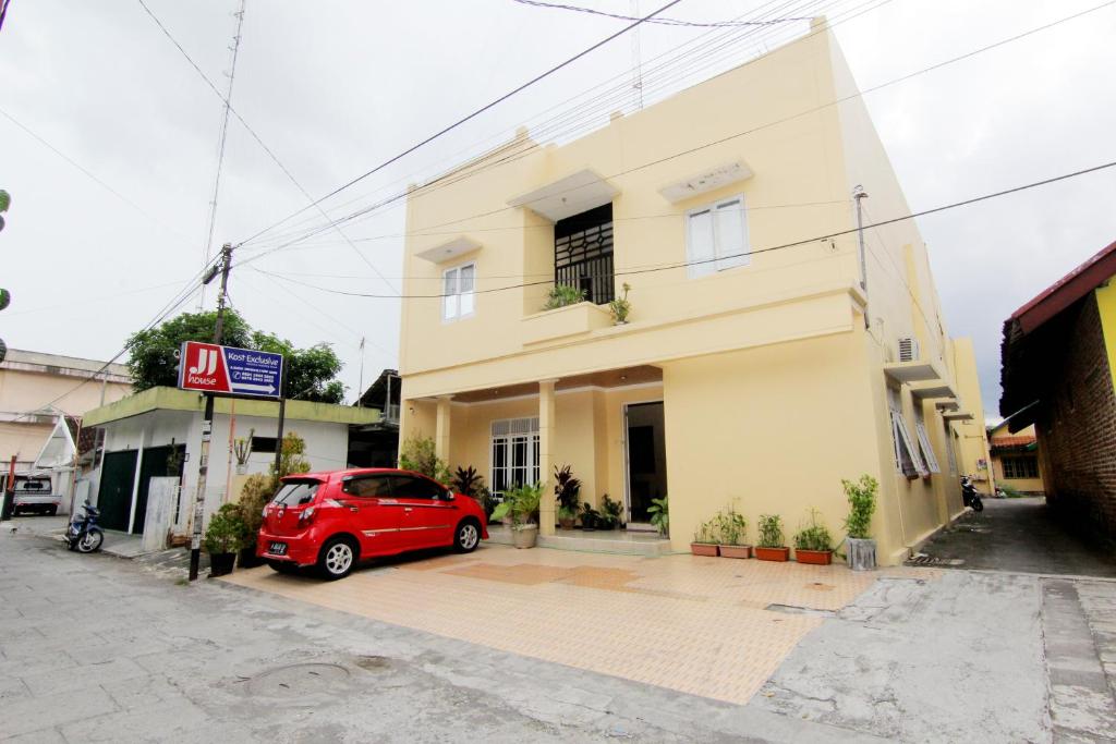 un'auto rossa parcheggiata davanti a un edificio di JJ House Gejayan a Yogyakarta