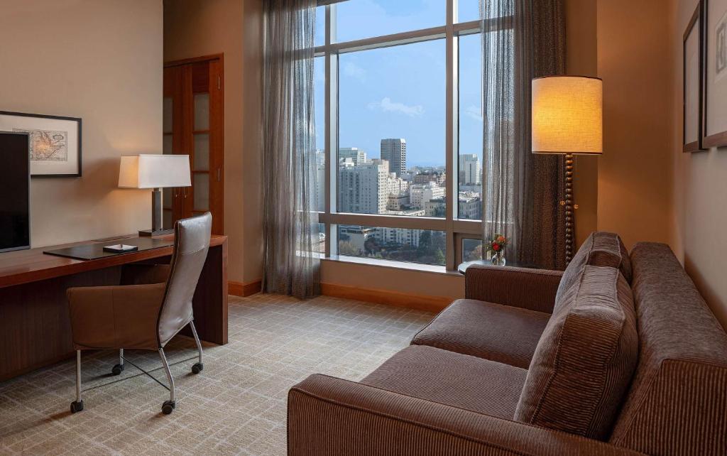 a living room with a couch and a desk and a large window at Grand Hyatt Seattle in Seattle