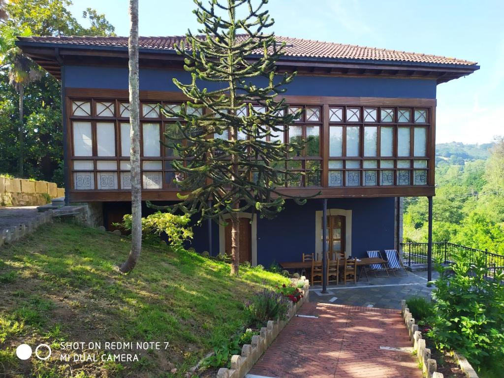 Ein blaues Haus mit einem Weg, der dorthin führt. in der Unterkunft Palacete Peñanora in Oviedo
