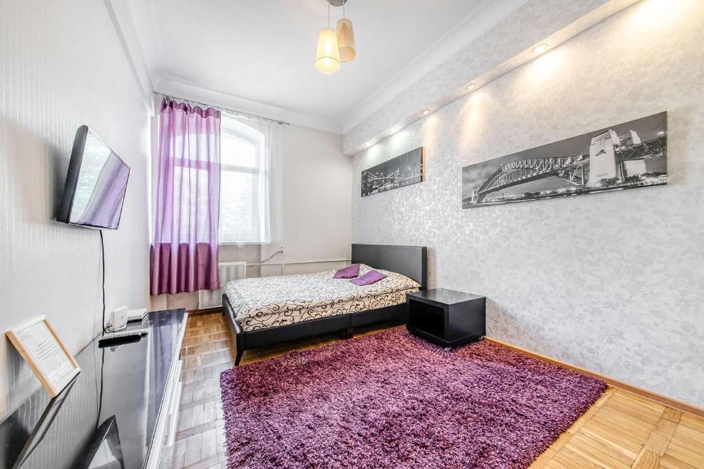 Habitación con cama, TV y alfombra. en Apartment on Karl Marx Street, en Minsk