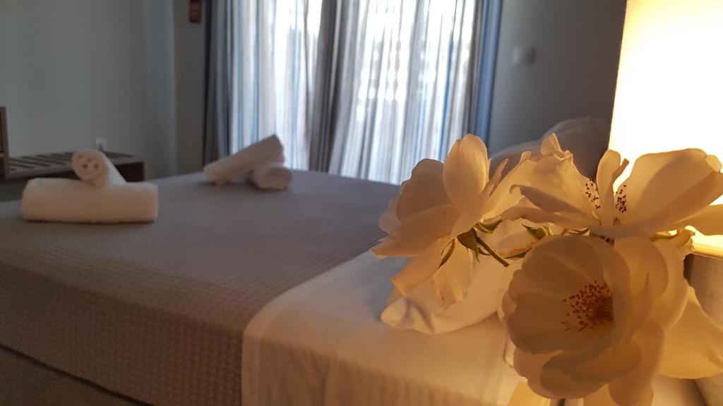 Una cama con dos toallas y flores. en CELENI APARTMENTS en Lefkada