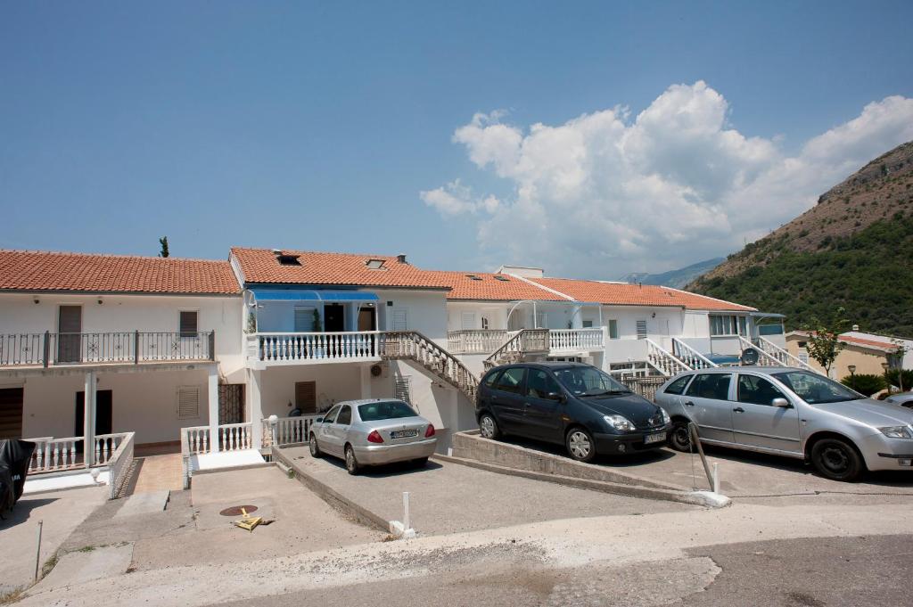 two cars parked in a parking lot in front of a house at Apartments Đurašević Ivo in Sveti Stefan