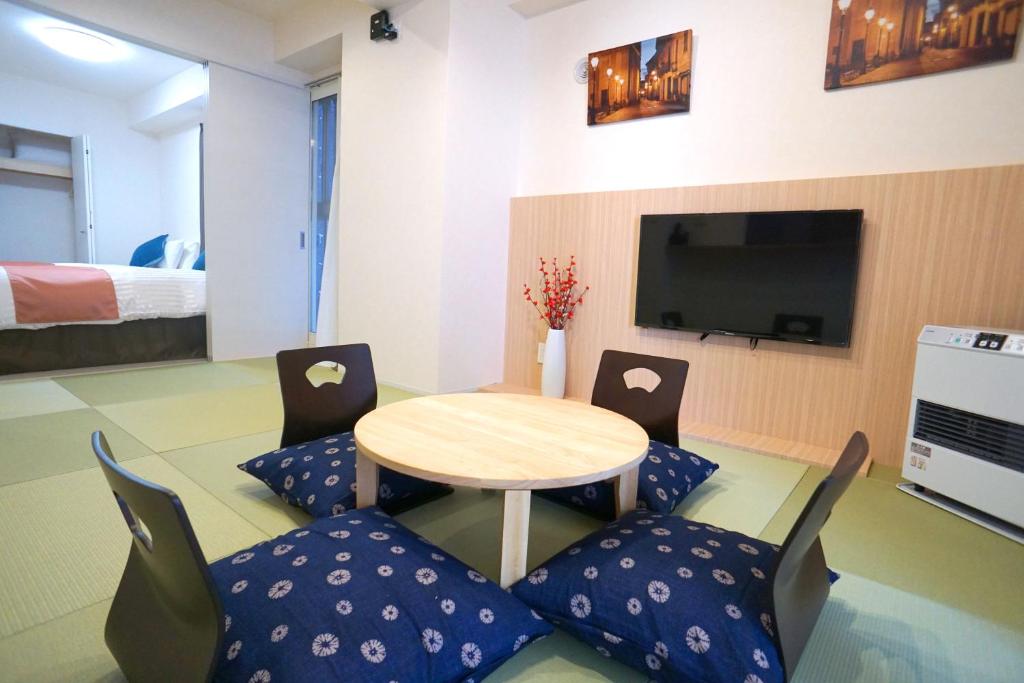 a room with a table and chairs and a tv at momo premium 401 in Sapporo