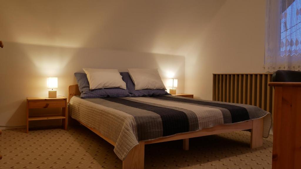 ein Schlafzimmer mit einem Bett mit zwei Nachttischen und zwei Lampen in der Unterkunft Herőke Vendégház in Terény