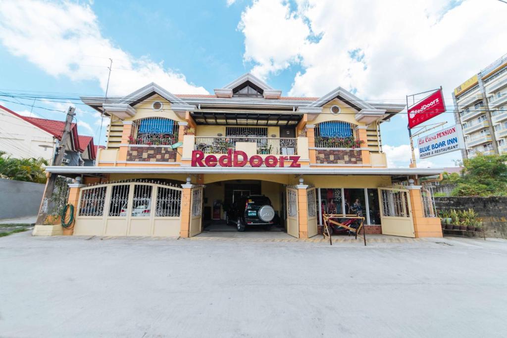 een gebouw met een rood bord aan de voorkant bij RedDoorz at La Casa Guesthouse former RedDoorz at Tamarind Street Angeles City in Angeles