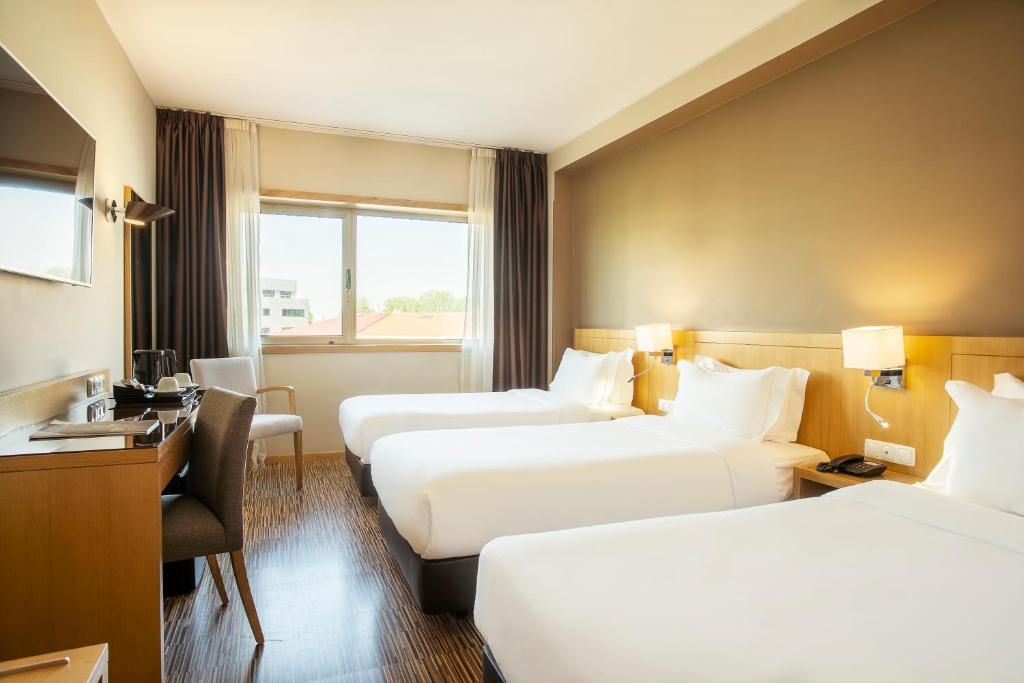 a hotel room with two beds and a desk at HF Tuela Porto in Porto