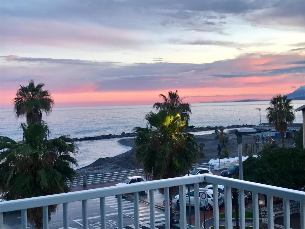 a balcony with a view of the ocean and palm trees at White Sand in Ventimiglia