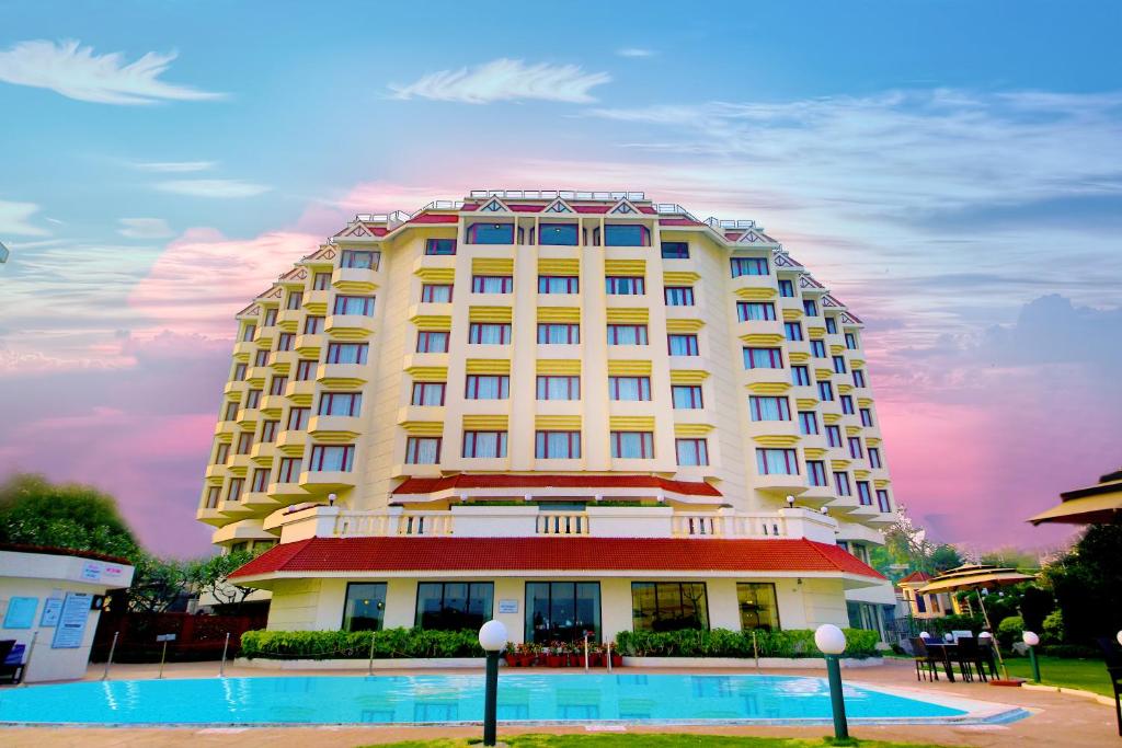 a large white building with a pool in front of it at Welcomhotel by ITC Hotels, Devee Grand Bay, Visakhapatnam in Visakhapatnam