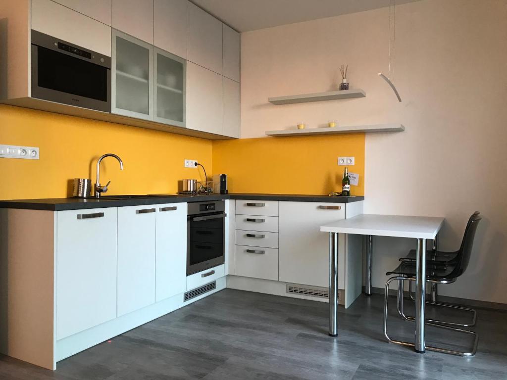 uma cozinha com armários brancos e uma mesa em apartmán Poděbradka em Plzeň