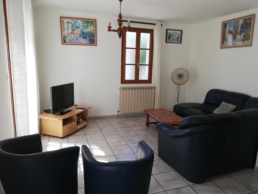 ein Wohnzimmer mit einem Sofa, Stühlen und einem TV in der Unterkunft villa rue gainekoa 1er étage in Cambo-les-Bains