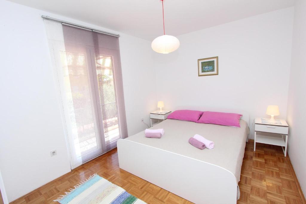 a white bedroom with a white bed and a window at Apartments Cocaletto in Rovinj