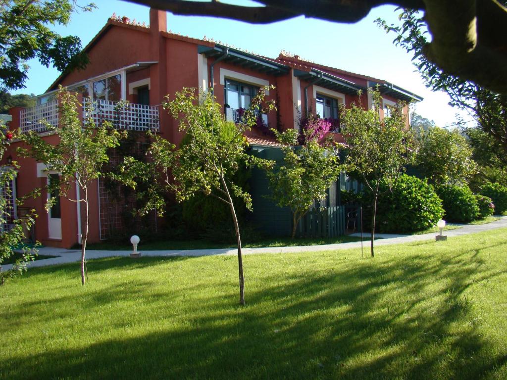 una casa roja con árboles delante de ella en Apartamentos del Norte en Andrín