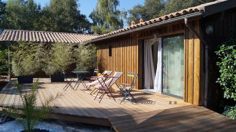 una terraza de madera con sillas y una mesa. en Le Domaine d'Azae, en Gujan-Mestras