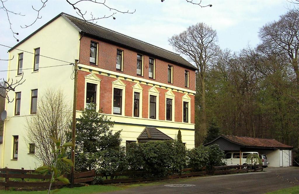 ein großes weißes und rotes Backsteingebäude in der Unterkunft Ehemaliges Waldkurhaus Drangstedt in Drangstedt