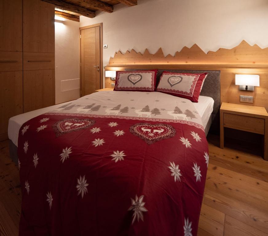 a bedroom with a bed with a red and white blanket at Stella Alpina Suite in Val di Zoldo