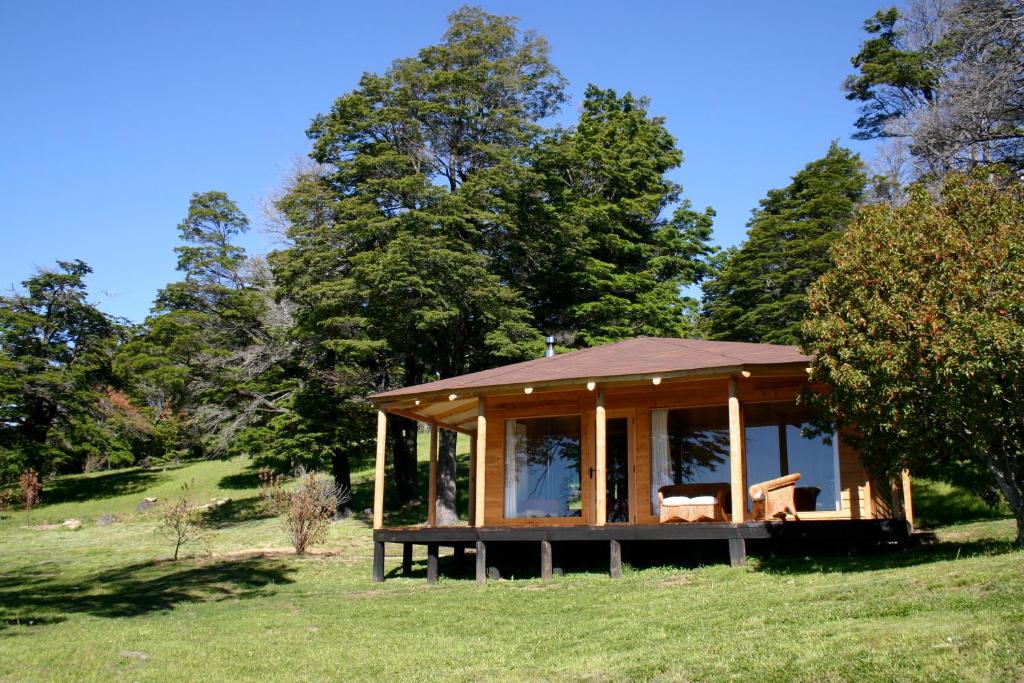 a cabin in the middle of a field with trees at Lodge El Mirador De Guadal in Puerto Guadal