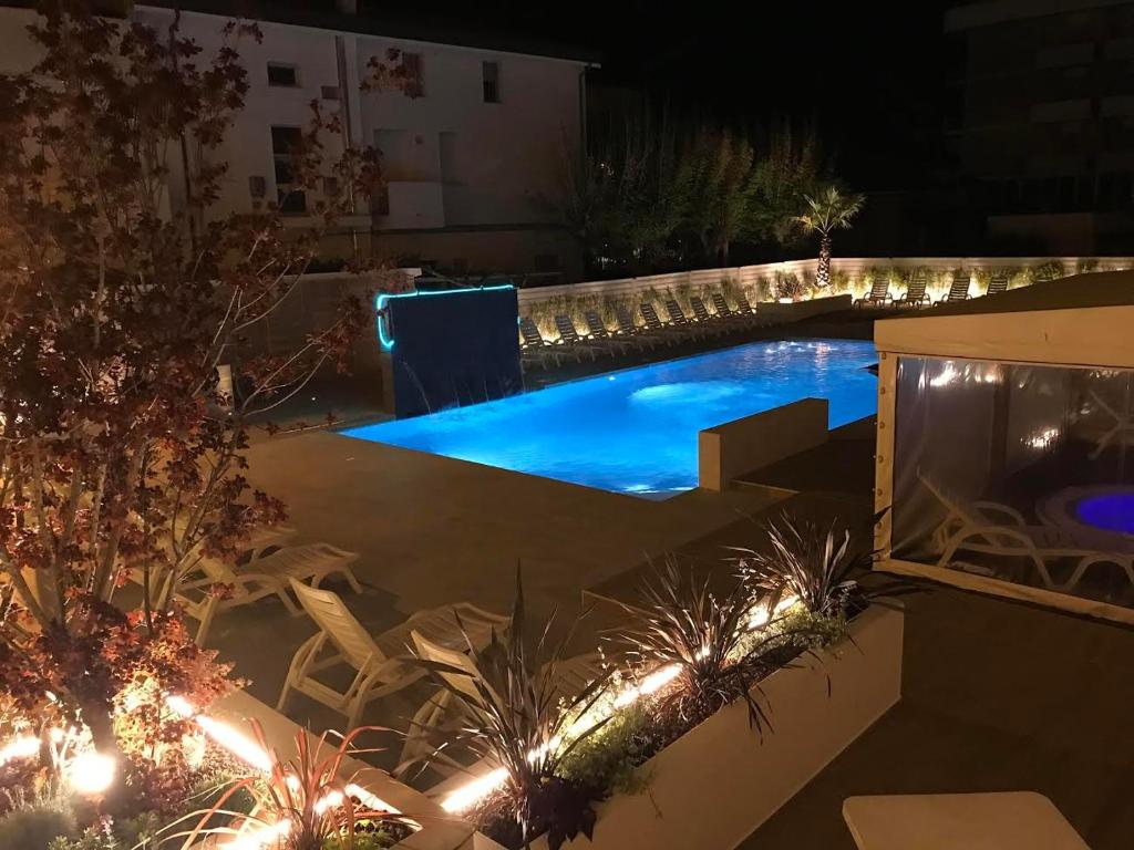 a backyard with a swimming pool at night at Hotel Milanese in Rimini