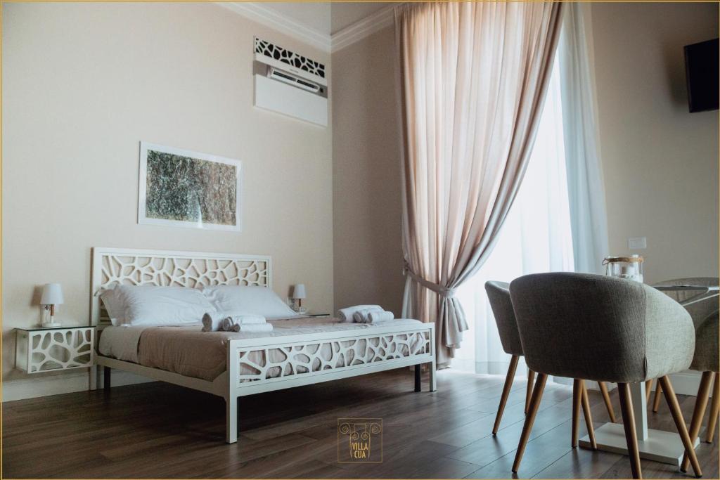 um quarto com uma cama, uma cadeira e uma janela em Villa Cua em Ercolano