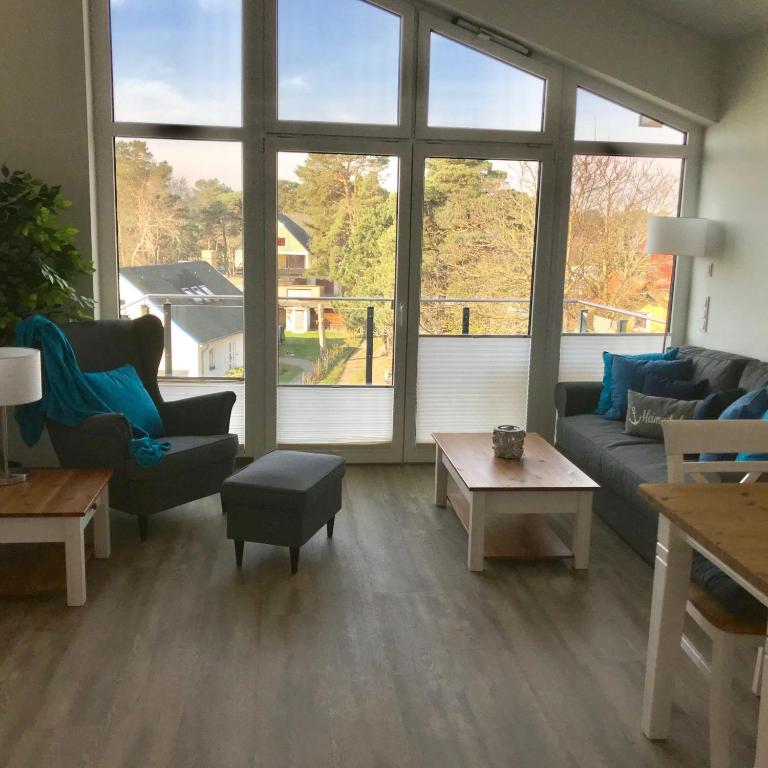 a living room with couches and tables and large windows at Ferienwohnung Oberdeck 2.06 in Glowe