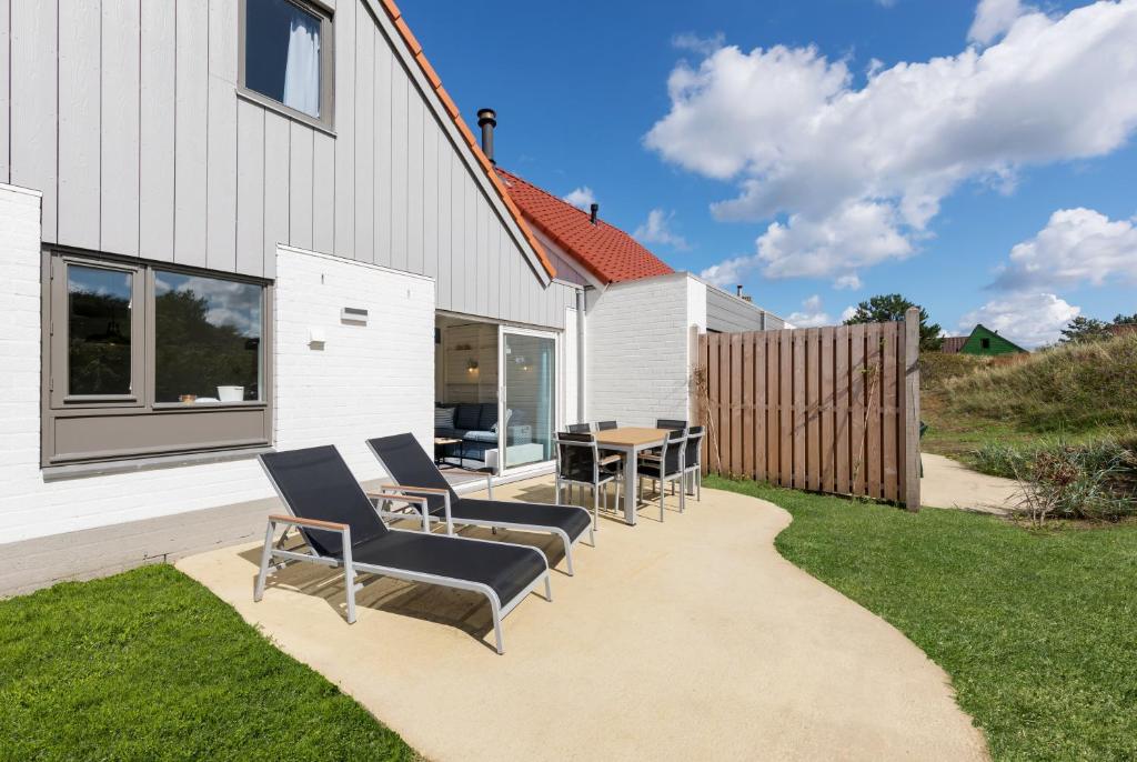 a patio with chairs and a table in front of a house at Center Parcs Zandvoort beach in Zandvoort