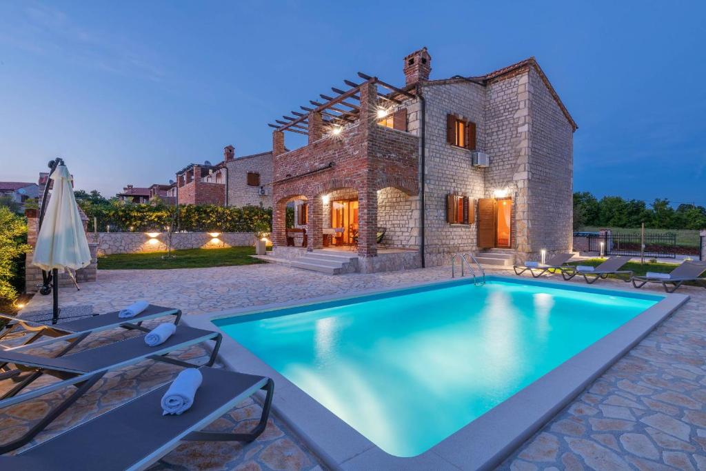 una villa con piscina di fronte a una casa di Villa Paradis 6 a Juršići