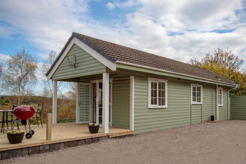 a green shed with a porch and a grill at Osprey lodge in Elgin