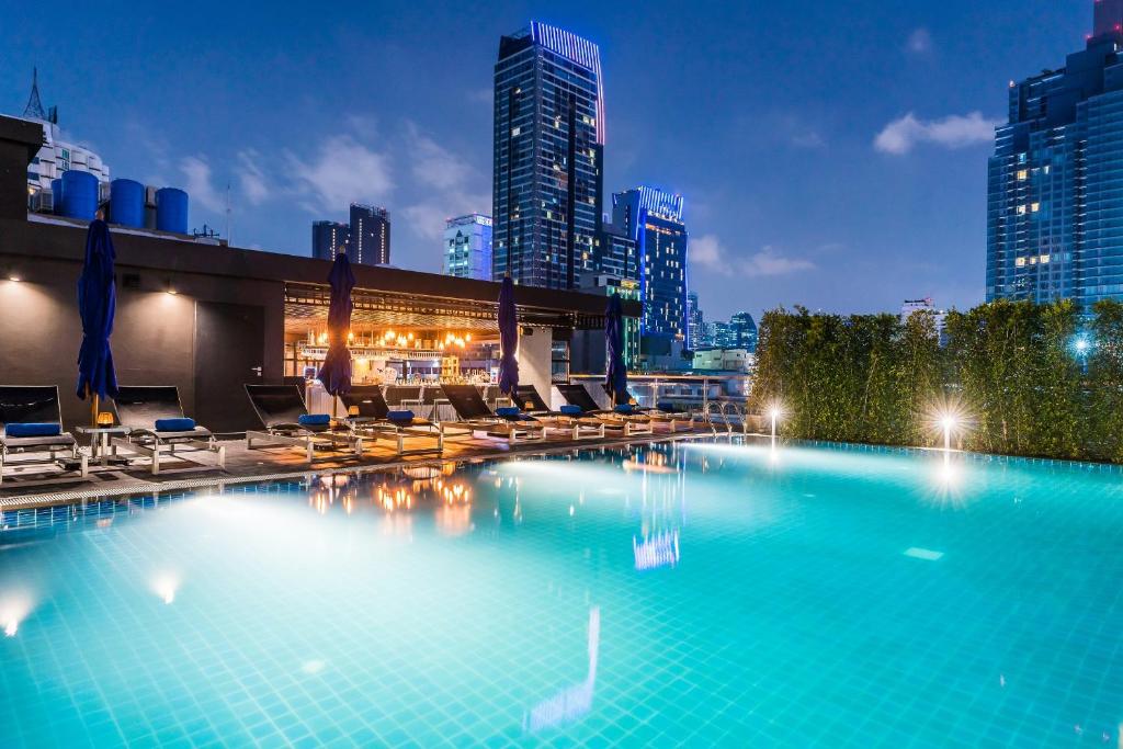 einen großen Pool mit Stühlen und eine Skyline der Stadt in der Unterkunft The Key Premier Hotel Sukhumvit Bangkok in Bangkok