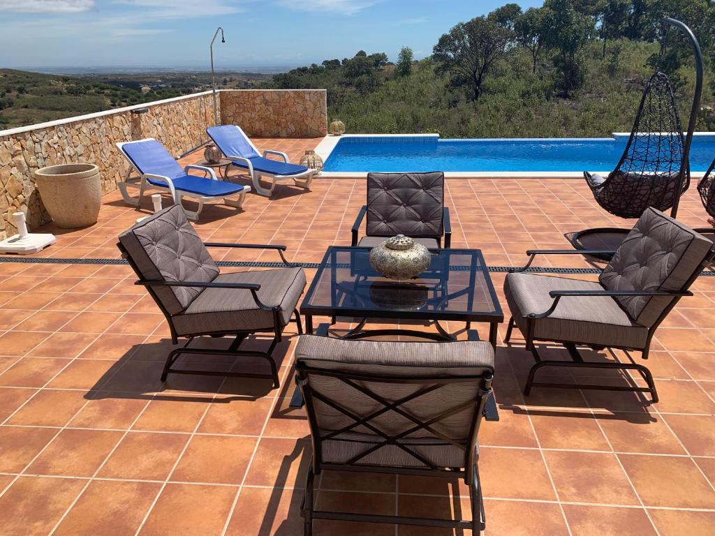 eine Terrasse mit Stühlen, einem Tisch und einem Pool in der Unterkunft Villa Vale Grande in Tavira