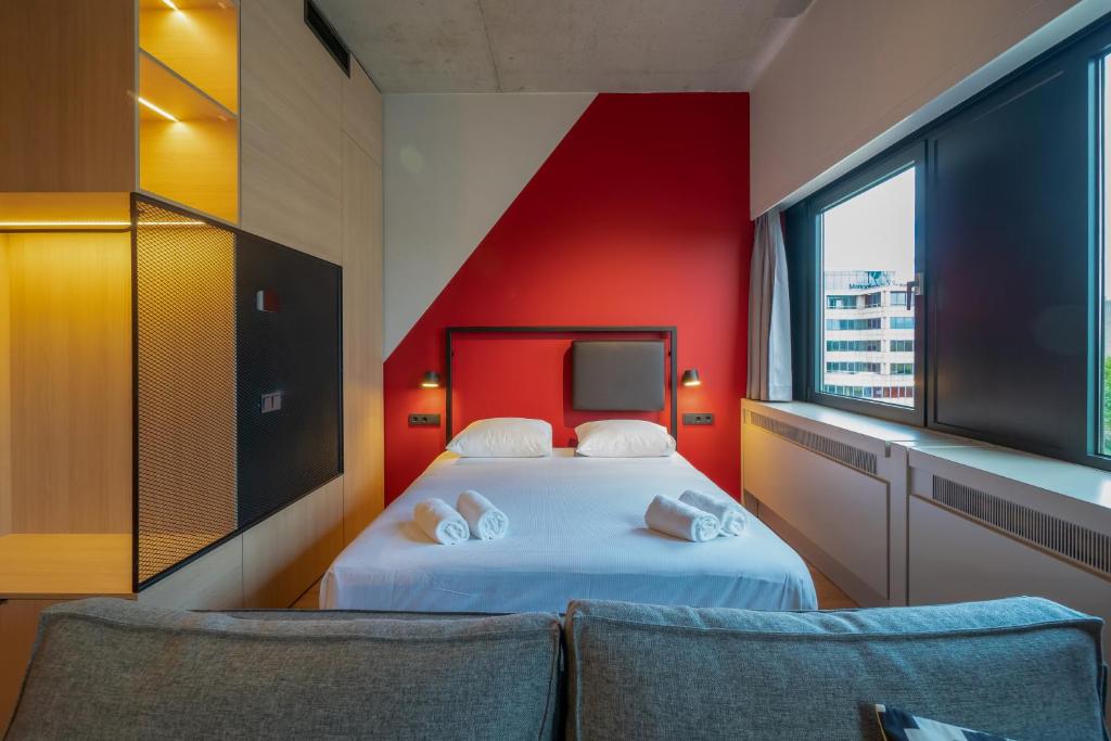 sypialnia z łóżkiem i czerwoną ścianą w obiekcie Via Suites w Amsterdamie