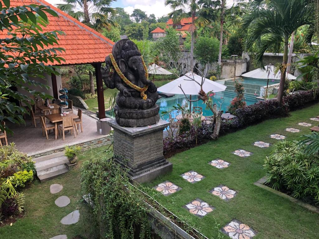 a statue in the yard of a resort with a pool at Betutu Bali Villas in Ubud