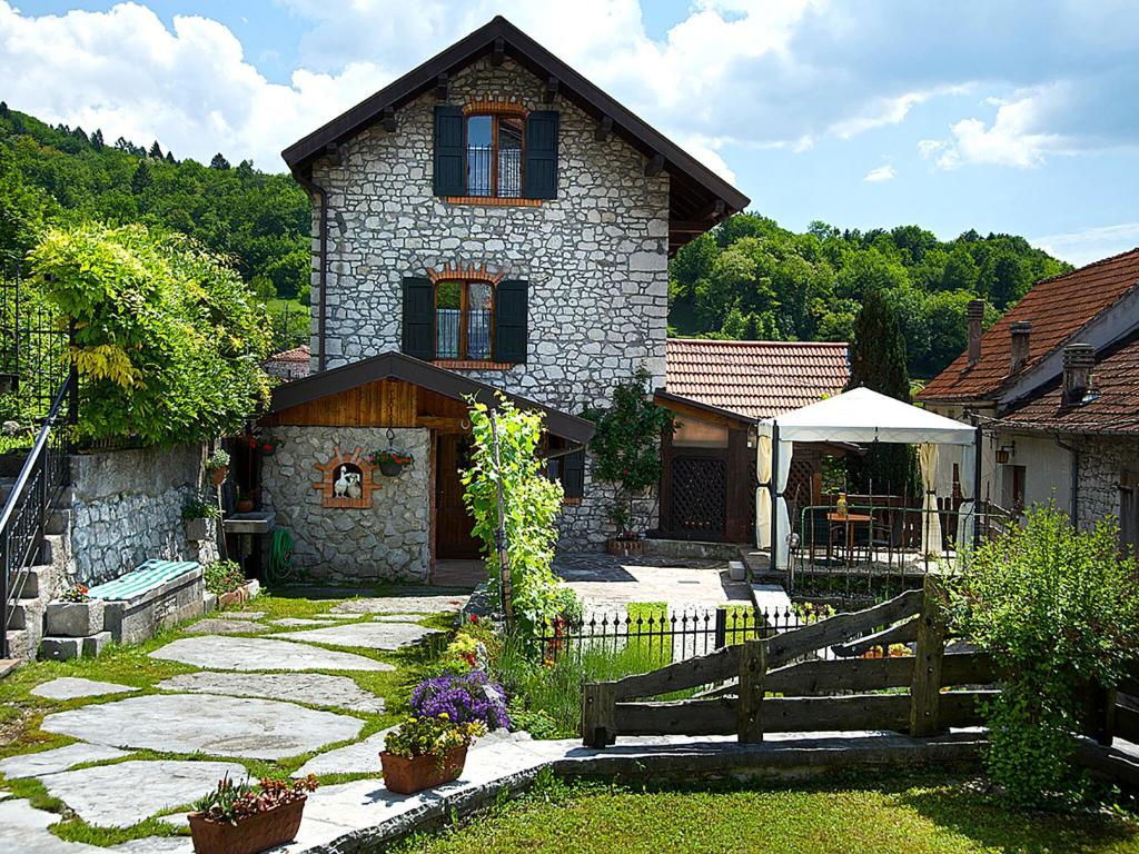 une maison en pierre avec une clôture devant elle dans l'établissement Belvilla by OYO Casa delle Alpi, à Ponte nellʼAlpi