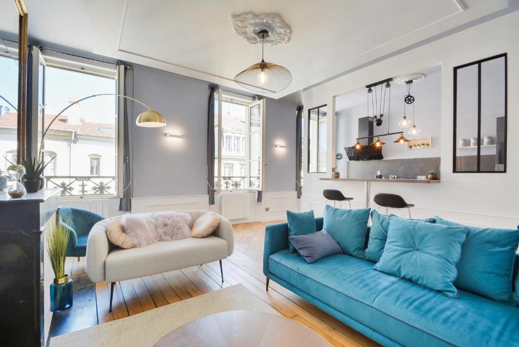 un salon avec un canapé bleu et une chaise dans l'établissement Le splendide de Stanislas, à Nancy